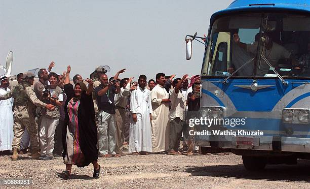 Bus load of freed Iraqi prisoners passes a group of waiting relatives after being released from Abu Ghraib prison May 21, 2004 outside of Baghdad,...