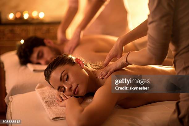 young couple enjoying at spa during back massage. - spa stock pictures, royalty-free photos & images