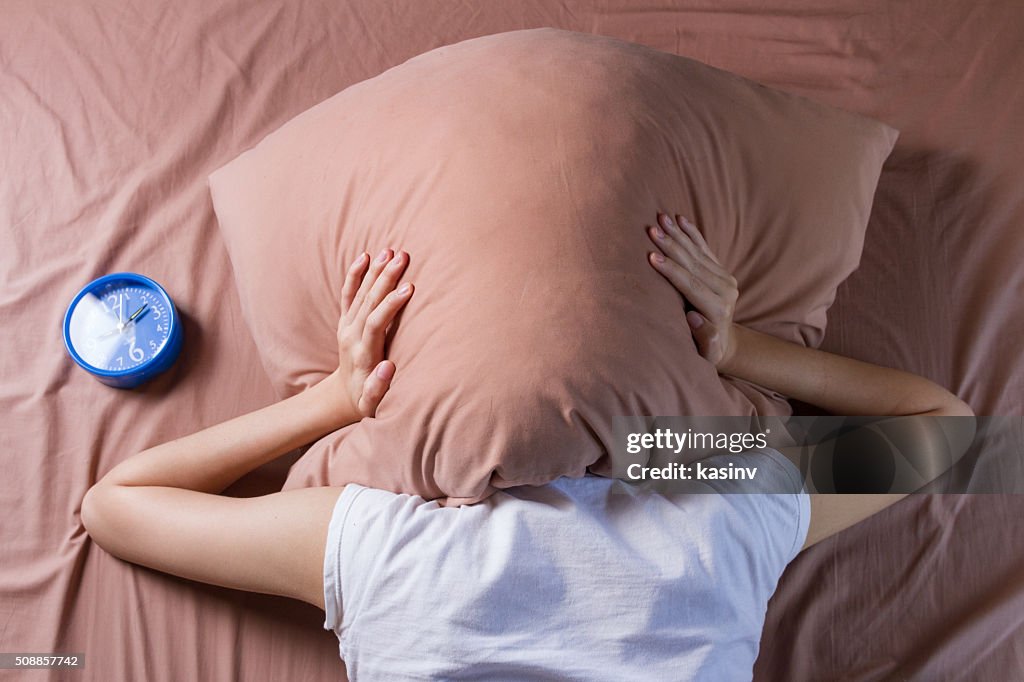 Woman cover her head with pillow