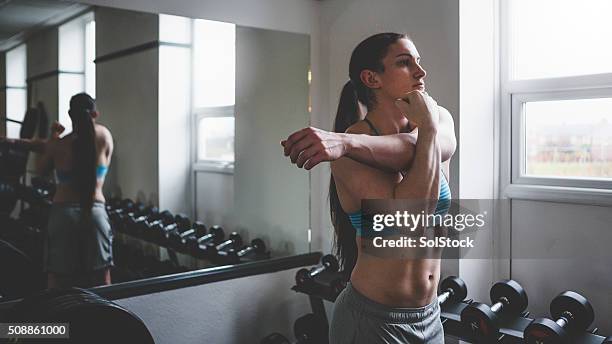 muscular woman doing arm stretch - deltoid stock pictures, royalty-free photos & images