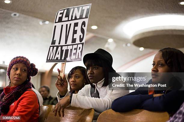 Dominique Strong Flint, Mich., holds up a sign during a city council meeting, which introduced the topic of whether Flint residents should have to...