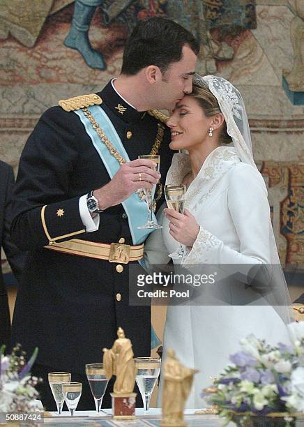 Crown Prince Felipe de Bourbon kisses his new wife Princess Letizia Ortiz during the celebratory wedding banquet at the royal palace May 22, 2004 in...