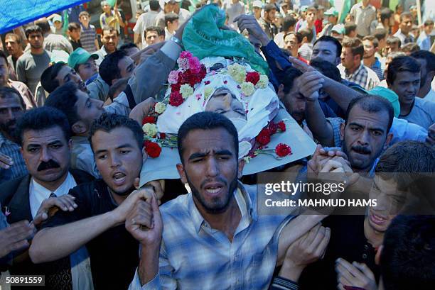 Palestinian men carry the body of Jamal al-Assar into his house during a mass funeral procession to bury 16 of those killed in Israel's offensive...