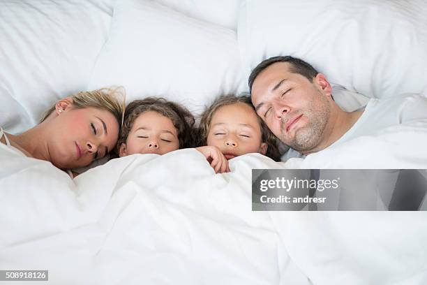 beautiful family sleeping together in bed - mattress stock pictures, royalty-free photos & images