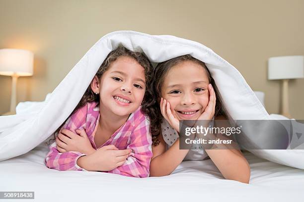 girls in bed under the covers - hotelroom stockfoto's en -beelden