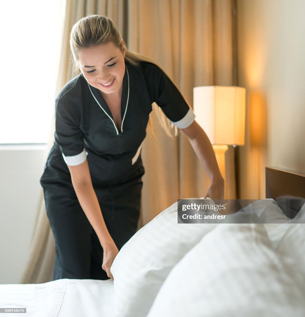 Housekeeper making the bed at a hotel