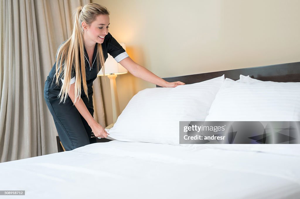 Maid working at a hotel making the bed