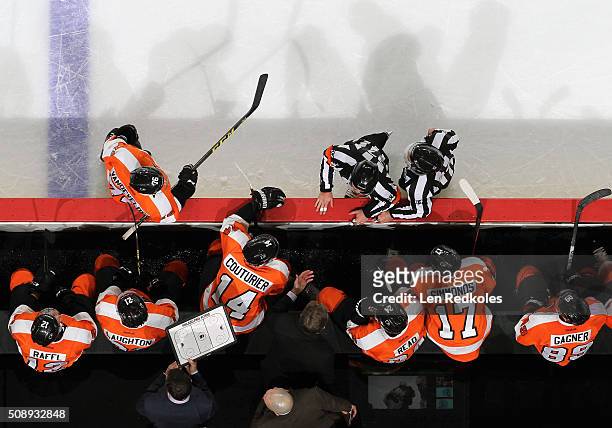Head Coach of the Philadelphia Flyers Dave Hakstol speaks with Referee Kyle Rehman and Linesman Brandon Gawryletz during a stoppage in play against...
