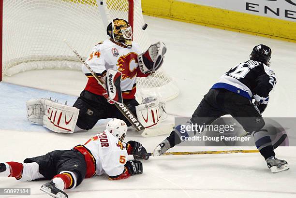 Goaltender Miikka Kiprusoff of the Calgary Flames makes a save on a shot by Martin St. Louis of the Tampa Bay Lightning as teammate Steve Montador...