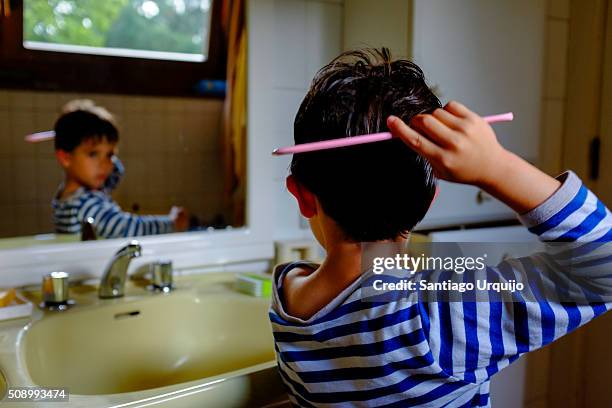 boy combing his hair in front of a mirror - comb stock pictures, royalty-free photos & images