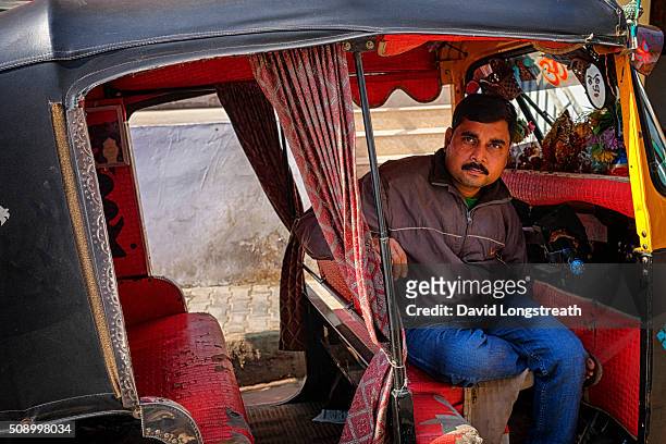 An Indian Tuk-Tuk driver looks on during morning rush hour as he waits for passengers.