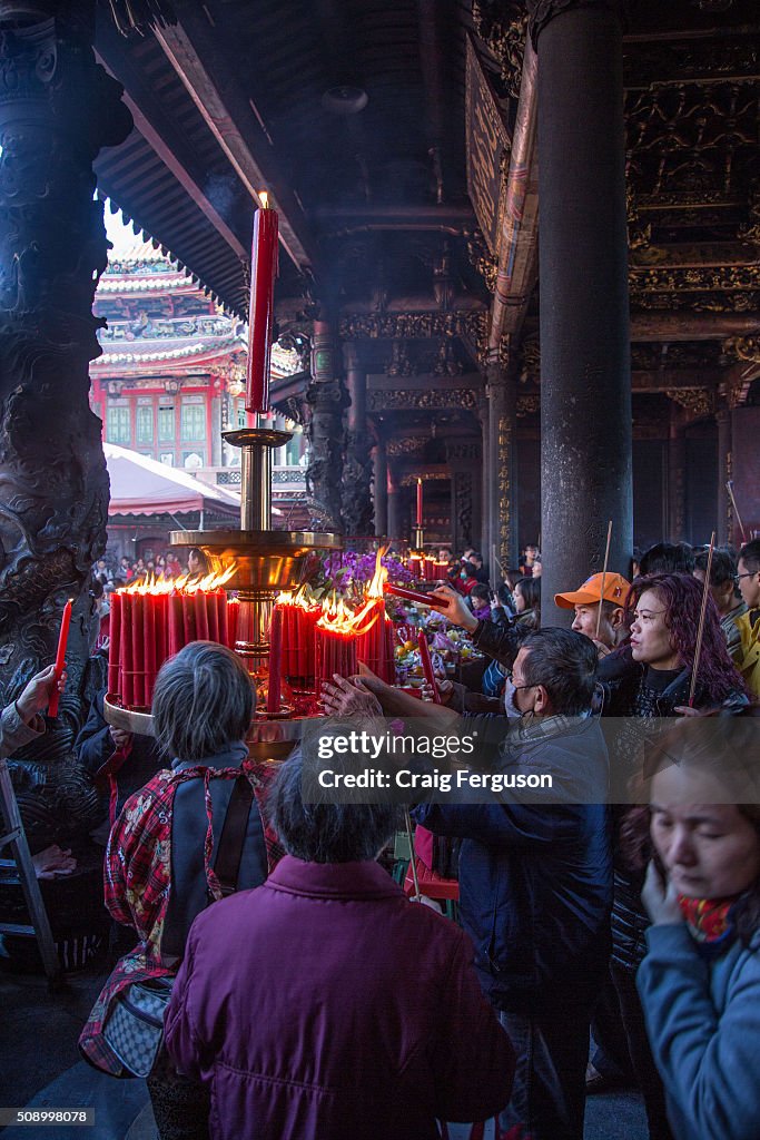 People light candles as the enter a temple to pray for an...