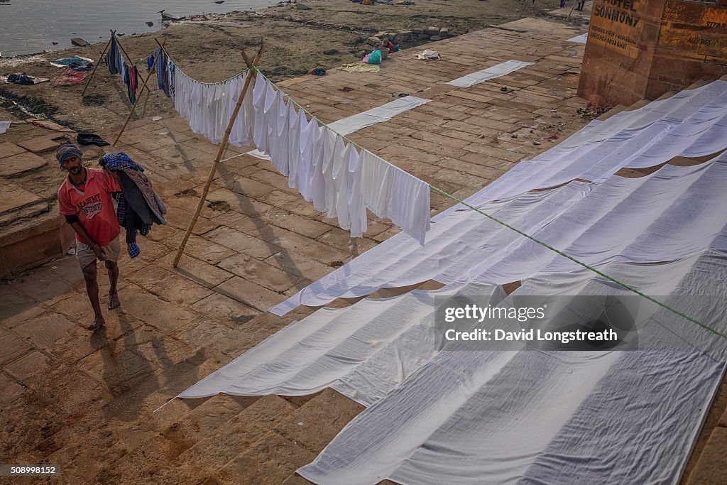 An Indian man hangs clothes to dry after washing them in the...