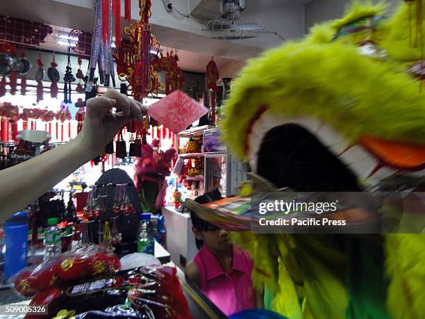 Filipino-Chinese storekeeper, left, hands a red envelope called 'ang bao' to a dragon dance performer inside a store in Manila's Chinatown. This year...