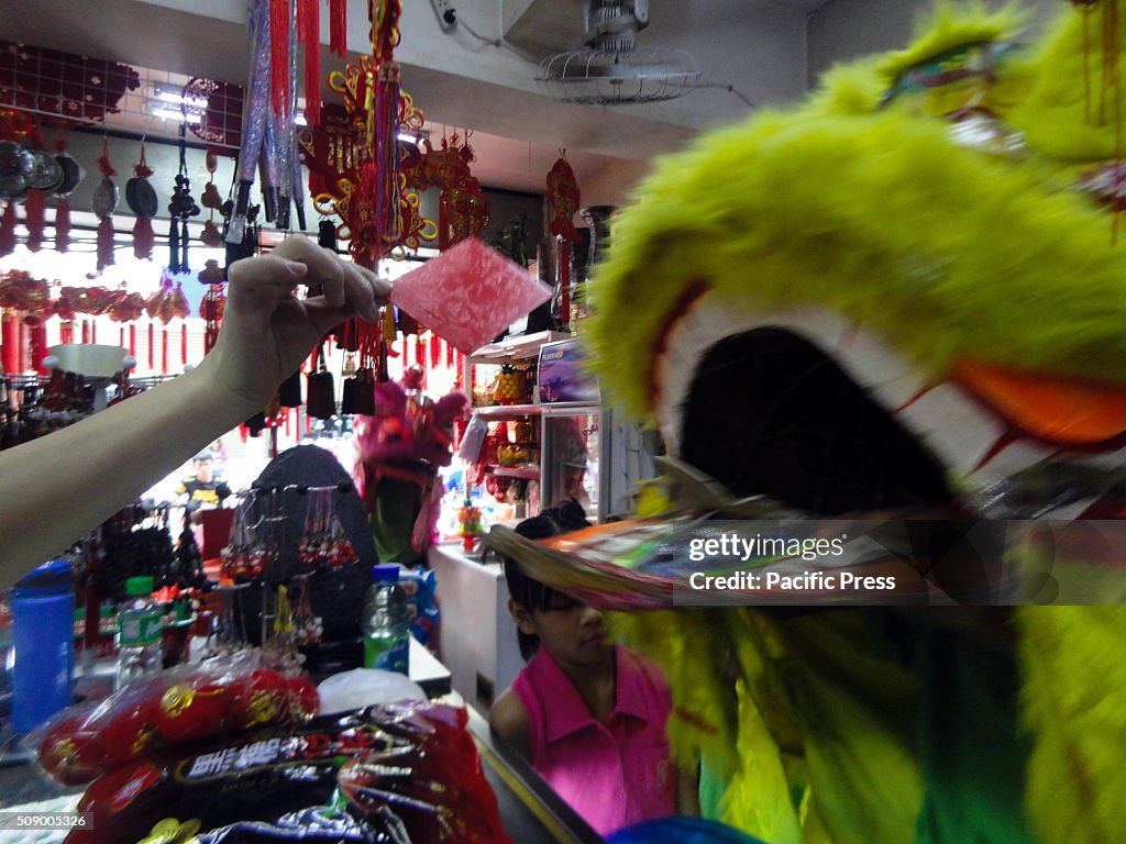 A Filipino-Chinese storekeeper, left, hands a red envelope...