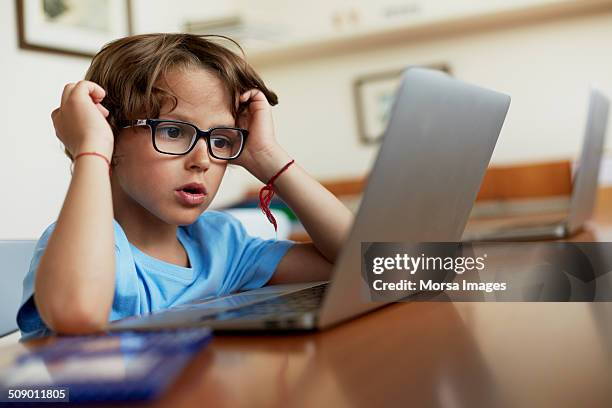 boy using laptop at table - kids eyeglasses stock pictures, royalty-free photos & images