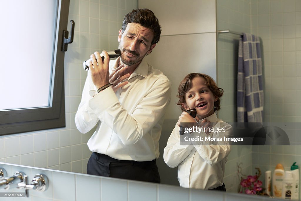 Reflection of father and son shaving together