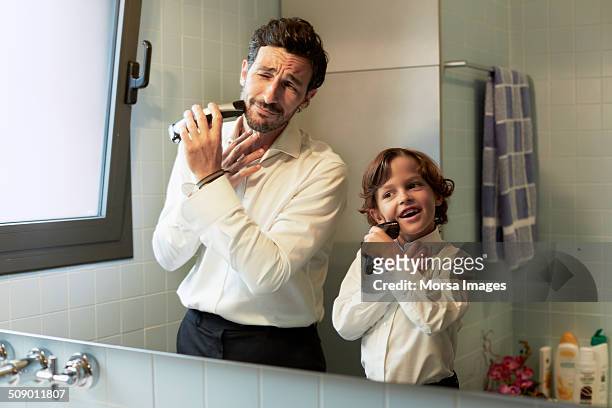 reflection of father and son shaving together - figlio maschio foto e immagini stock