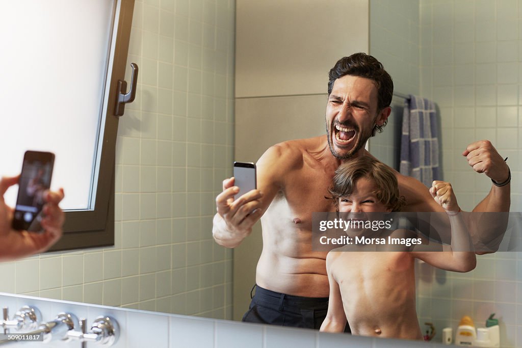 Father and son photographing while flexing muscles