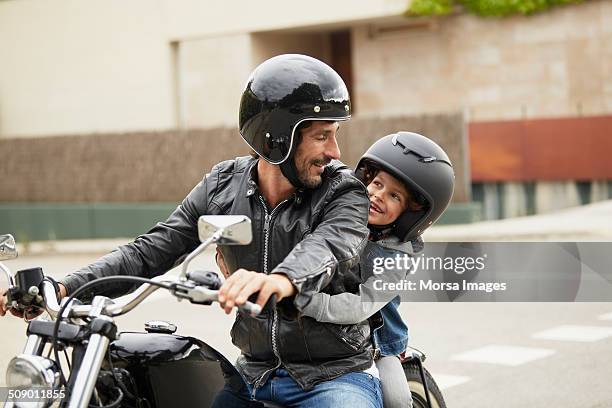 father and son riding motorbike - protection helmet stock-fotos und bilder