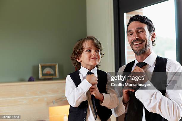 boy adjusting tie while looking at father - caricatura fotografías e imágenes de stock