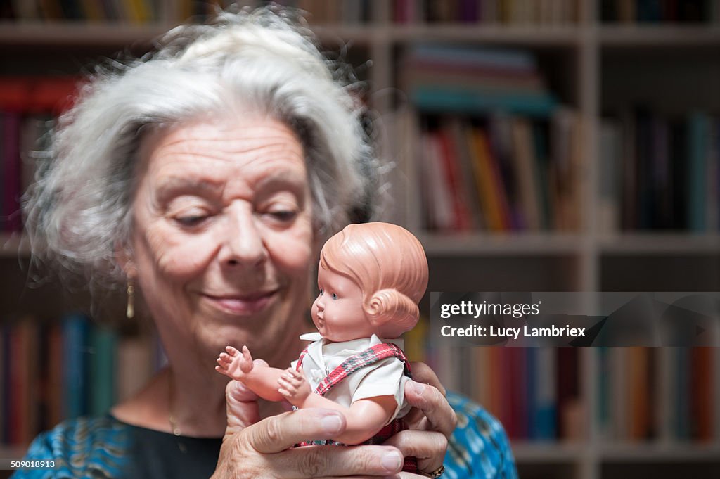 Senior woman cuddling with her childhood doll