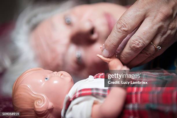 senior woman holding hands with her doll - doll stock pictures, royalty-free photos & images