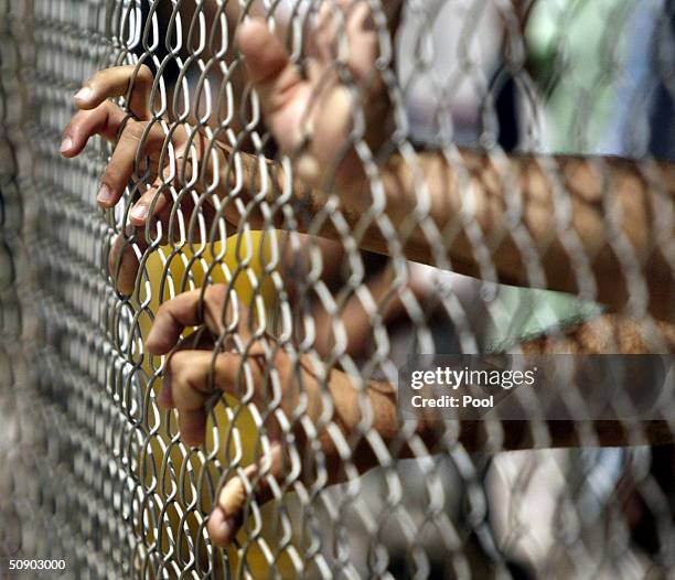 Detainees at Abu Ghraib prison reach hold the fence at a new section of the prison named Camp Redemption May 26, 2004 in Baghdad, Iraq. The U.S....