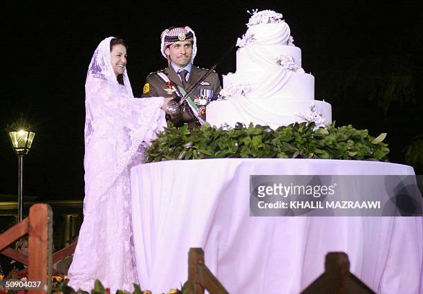 Jordan's Crown Prince Hamza and his bride Princess Noor cut the cake during their wedding party at Amman's Zaharan palace 27 May 2004. Hundreds of...