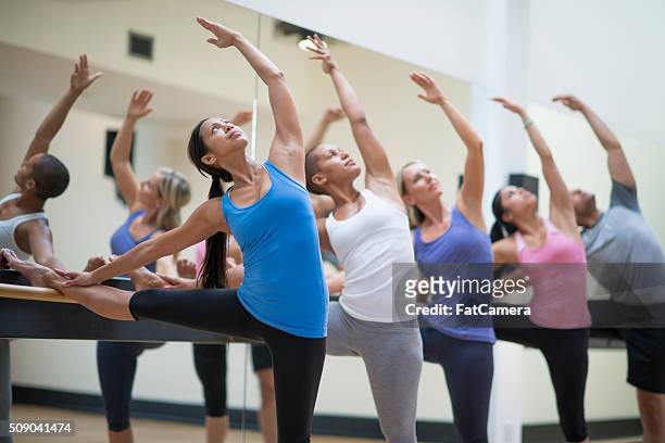 stretching during a barre class - bars stockfoto's en -beelden
