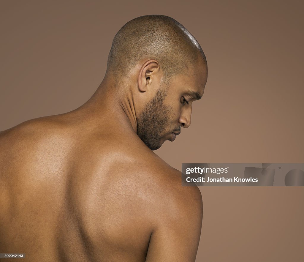 Athletic dark skinned male looking over shoulder