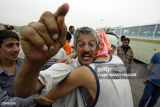 Prisoner, one of 600, gestures as he is hugged by a relative following his release from the Abu Ghraib prison, west of Baghdad, 28 May 2004. US...
