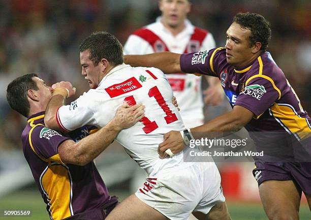 Dean Young of the Dragons fends off the tackle of Ben Ikin and Neville Costigan of the Broncos during the NRL match between the Brisbane Broncos and...