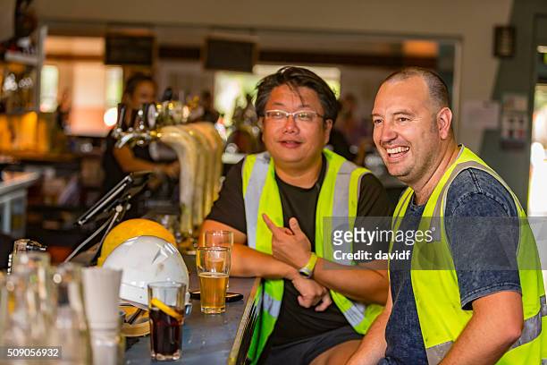 workmen relaxing with beer after work in high visibility clothes - australian pub stock pictures, royalty-free photos & images