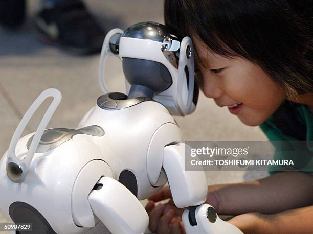 Boy plays with Sony's latest entertainment robot dog, AIBO ERS-7 during AIBO's 5th anniversary exhibition in Tokyo 29 May 2004. More than 130,000...