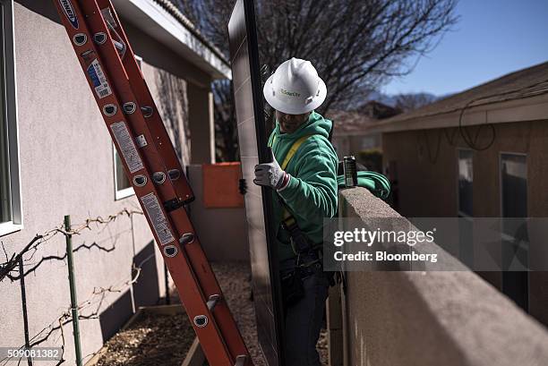 Worker moves a solar panel towards a roof during a SolarCity Corp. Residential installation in Albuquerque, New Mexico, U.S., on Monday, Feb. 8,...