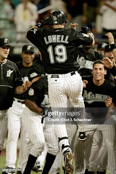 Third baseman Mike Lowell of the Florida Marlins jumps into his teammates after hitting a 10th inning home run to beat the New York Mets, 3-2, May...