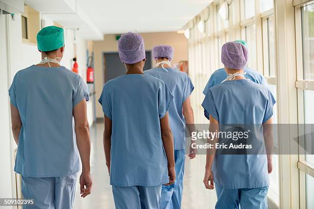 rear view of a medical team walking in the corridor of a hospital - nurse walking stock pictures, royalty-free photos & images