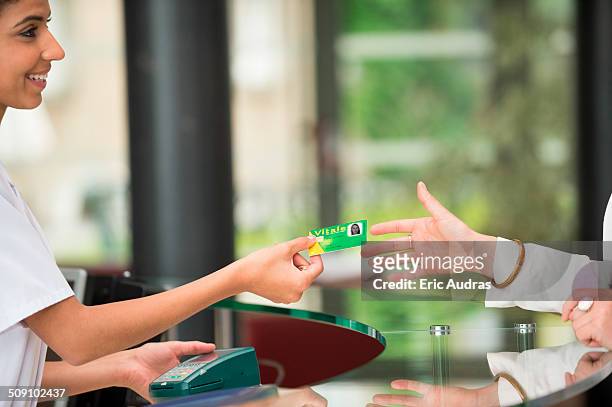 woman giving french social security card to receptionist at hospital reception desk - social security stock pictures, royalty-free photos & images