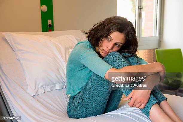 female depressed patient sitting on the bed in a hospital ward - hugging knees stock pictures, royalty-free photos & images