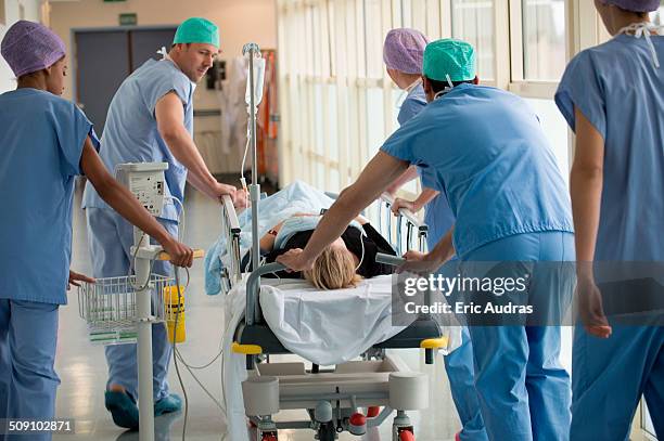 medical professionals pushing patient on gurney in a hospital - hospital gurney stock pictures, royalty-free photos & images