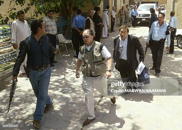 An armed guard escorts a Japanese forensic expert and Japanese medic as the vehicle carrying the two bodies of Japanese journalists killed two days...