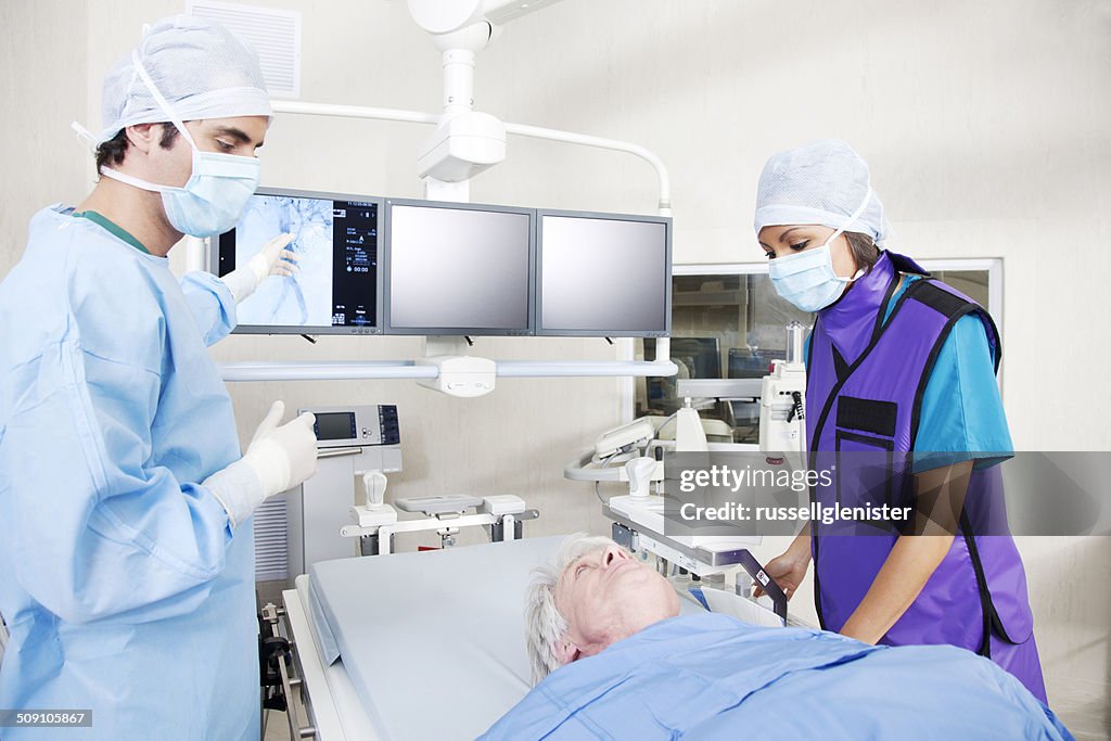 Surgeon and nurse analysing MRI scan with patient in operating theatre