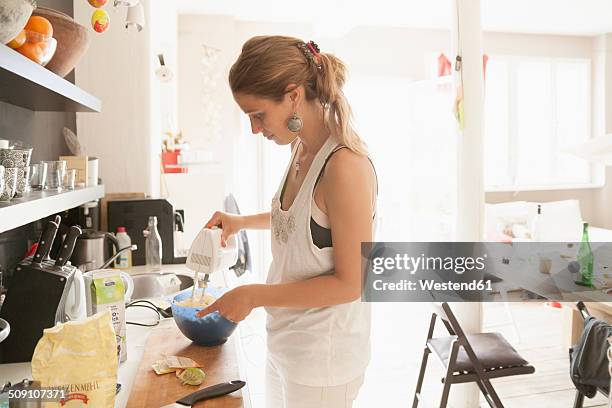 young woman mixing dough at kitchen - baking powder stock pictures, royalty-free photos & images