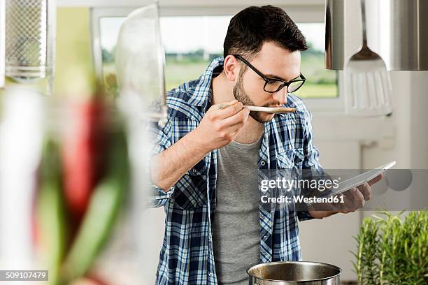 young man cooking in kitchen at home - man glasses tablet in kitchen stock pictures, royalty-free photos & images