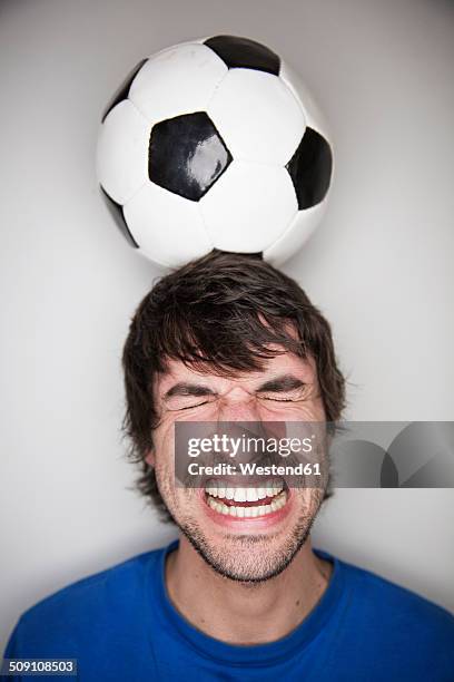 young man balancing soccer ball on head - grimacing stock pictures, royalty-free photos & images