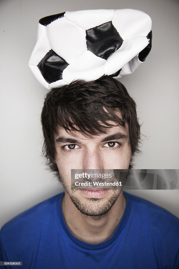Young man balancing deflated soccer ball on head