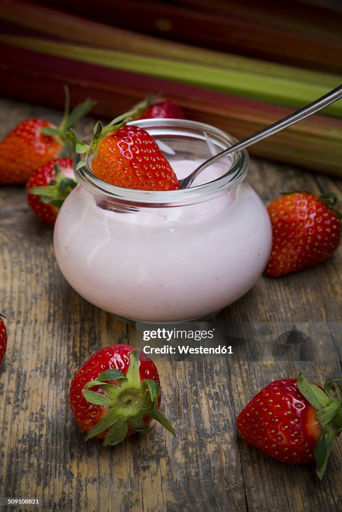 Glass of strawberry yoghurt, strawberries and rhubarb on dark wood