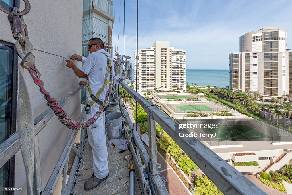 Painter Clearing the Cracks on a Highrise Building Being Prepped