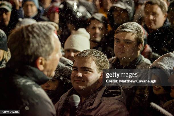 Supporters stand in the snow as Republican presidential candidate, Ohio Gov. John Kasich speaks at an election eve rally on February 8, 2016 at...